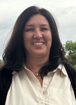 Frau mit Seidenbluse und schwarzem Blazer vor einer Wiese