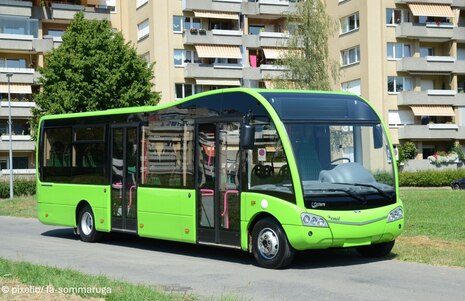 Grüner Elektrobus vor einem Neubaublock